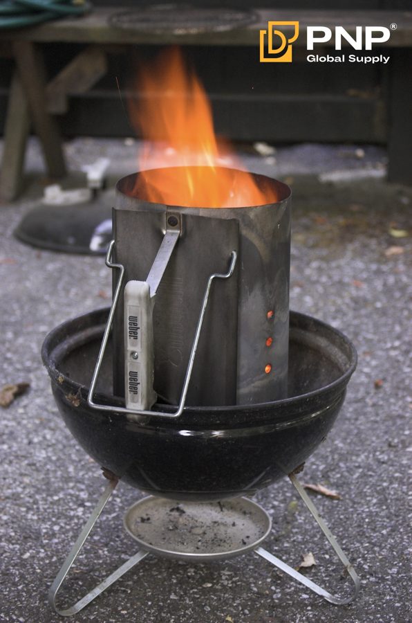 A chimney starter prepares hot coals before they are arranged for grilling